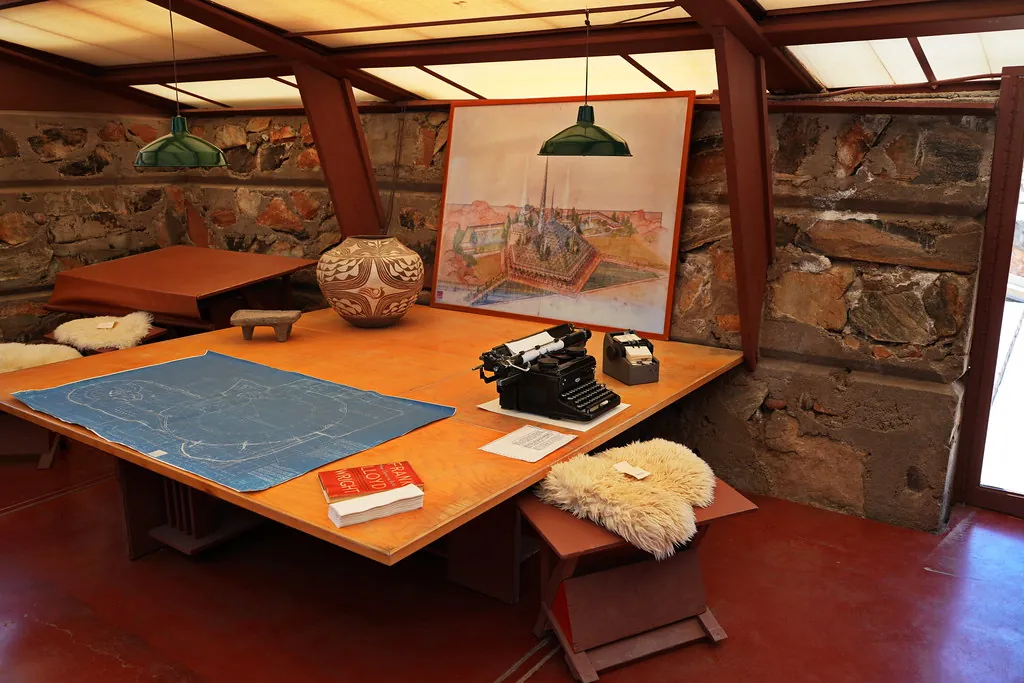 Mesa de trabajo del taller con maqueta, planos y libros de referencia